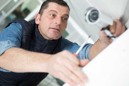 technician installing cctv camera on wall indoorsの写真素材
