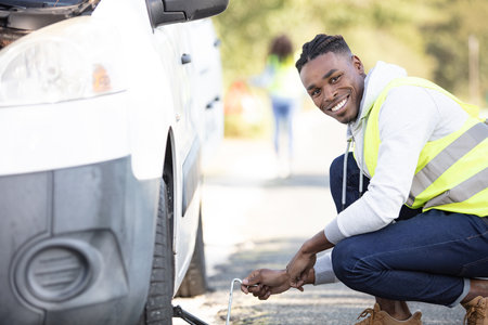 auto mechanic changing tire on car on roadの写真素材
