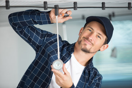 young electrician installing a lamp on the ceilingの写真素材