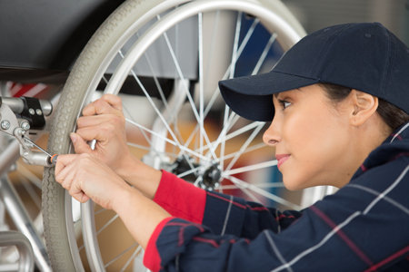 female worker adjusting brakes on a wheelchairの写真素材