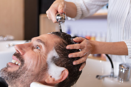female barber washing head of male client in barbershop