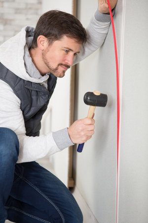 man hammering cable into recessの写真素材