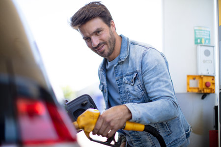 man pumping gasoline fuel in car at gas stationの写真素材