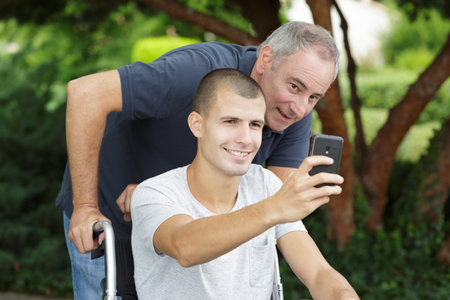 disabled son taking selfie with his dadの写真素材