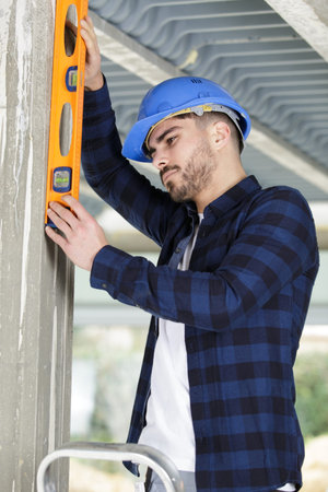 mason checking horizontal level of house wall