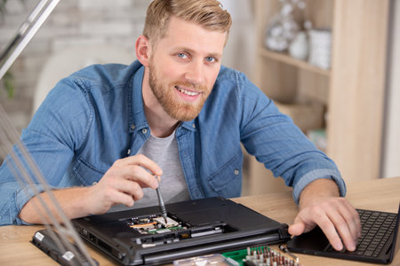 young energetic male tech or engineer repairs laptopの写真素材