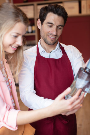 smiling man with a woman buys wine bottleの写真素材