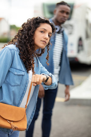 young woman waits at bus station looks at watch