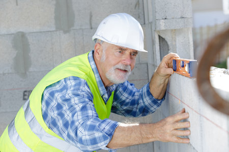 senior male worker measuring wallの写真素材