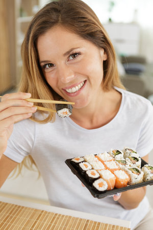 smiling young woman eating sushiの写真素材