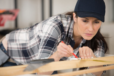 female carpenter marking position on woodの写真素材