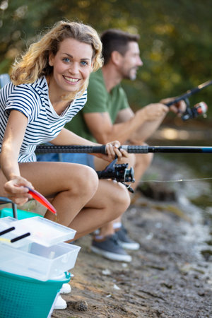 happy adult couple fishing on riverbank