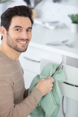 man wiping cutlery in the homeの写真素材