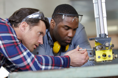 carpenter teaching apprentice how to cut woodの写真素材
