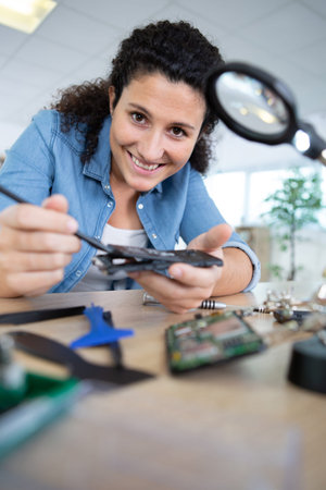 female engineer looking at circuit through magnifying glass