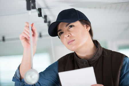 a woman worker installs a new lightの写真素材