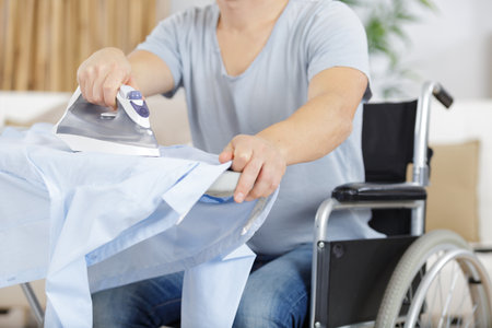 disabled man on wheelchair ironing clothingの写真素材