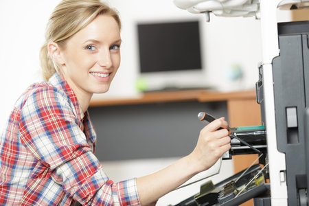 happy woman repairing an office printerの写真素材