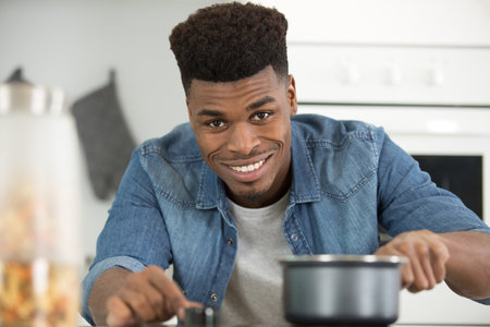 handsome young man cooking pasta in the kitchen at homeの写真素材
