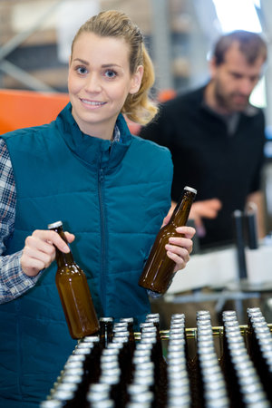 happy female brewery worker with bottling machinery on factoryの写真素材