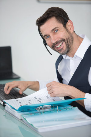 smiling businessman using headset while talking to customer