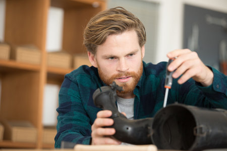 mechanic using screwdriver on dismantled hoseの写真素材