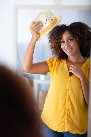 beautiful afro american girl is fitting on stylish straw hatの写真素材
