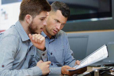 two men reading and discussing papers
