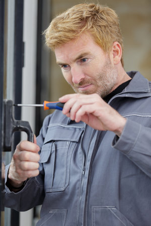 service man installing window with screwdriverの写真素材