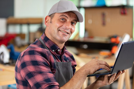 smiling manual worker holding and using a laptop