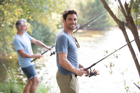 men friends fishing together at the river