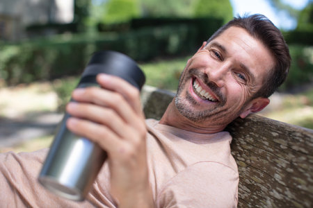 man drinkis coffee on a benchの写真素材