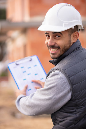 portrait of smiling handyman showing clipboardの写真素材