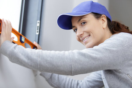 female decorator measuring the level of a window frameの写真素材