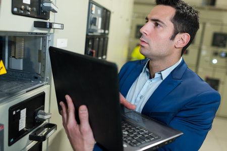 man with laptop standing by server cabinet