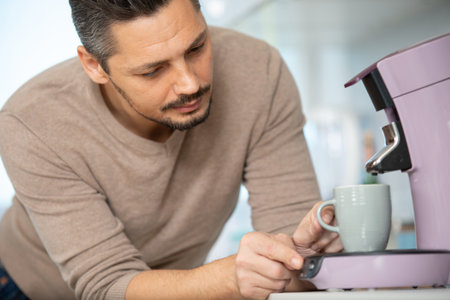 handsome man making coffee with a coffee machineの写真素材
