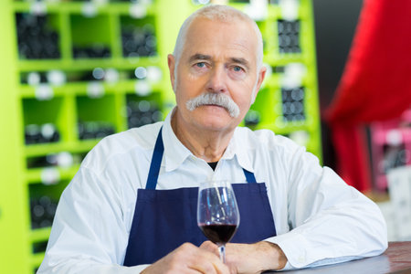 vendor on apron holding a glass of wineの写真素材