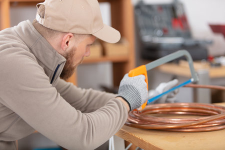 male craftsman sawing copper pipe