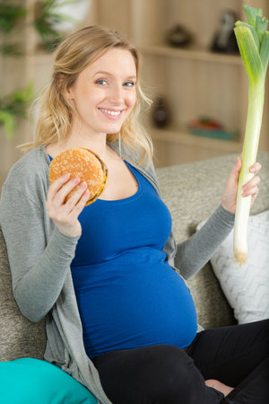 pregnant woman with burger and vegetablesの写真素材