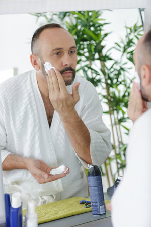 mature man applying shaving cream to faceの写真素材
