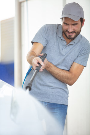 handsome washer cleaning a car at the open air carwashの写真素材