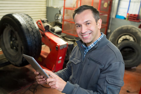 mature tire mechanic holding tabletの写真素材