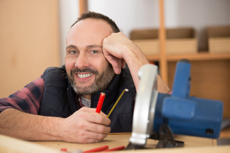 happy confident middle-aged bearded carpenter posing and smilingの写真素材