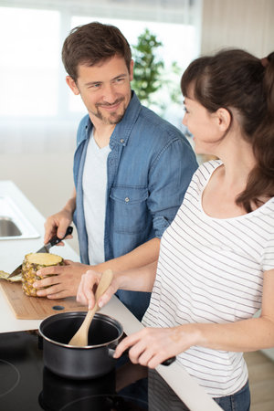 smiling young couple cooking food in the kitchenの写真素材