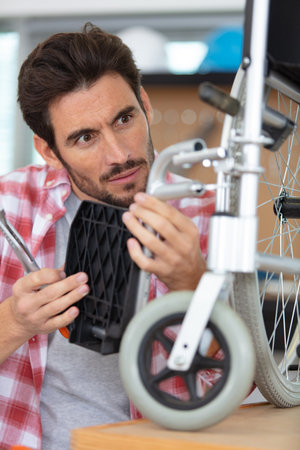 man is repairing a wheelchair in garageの写真素材