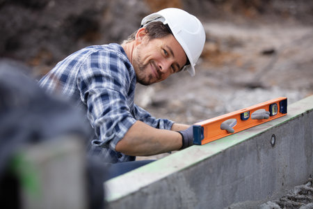 bricklayer putting down another row of bricks in siteの写真素材