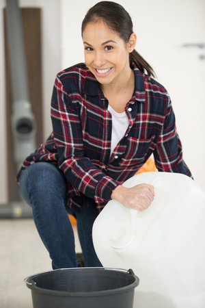woman pouring from a large plastic containerの写真素材