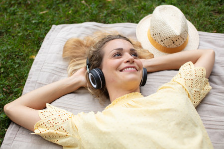 woman lies on the grass listens to music on headphonesの写真素材