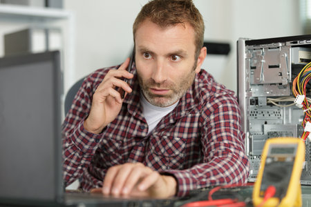 technician repairing a computer and phone to the customerの写真素材