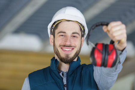 happy young worker with earmuffs in noise canceling conceptの写真素材